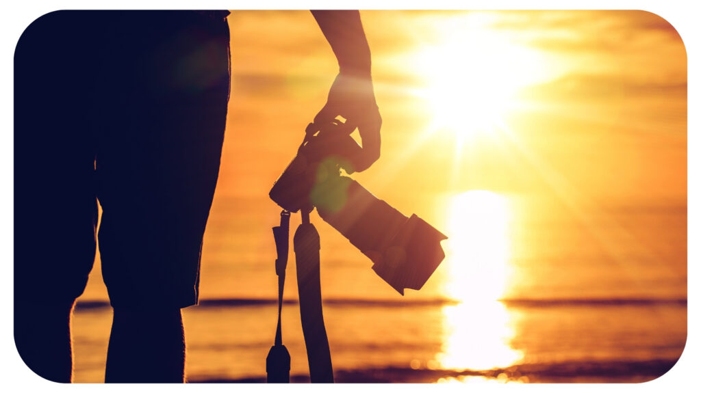 holding camera at beach sunrise