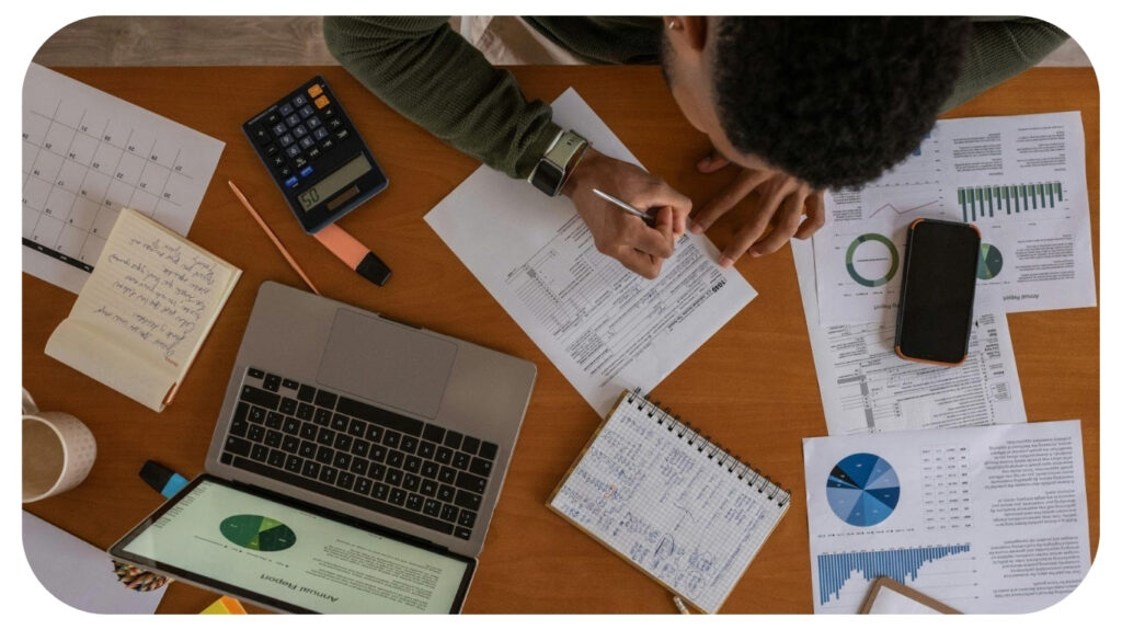 a person sitting at a table with papers and a laptop