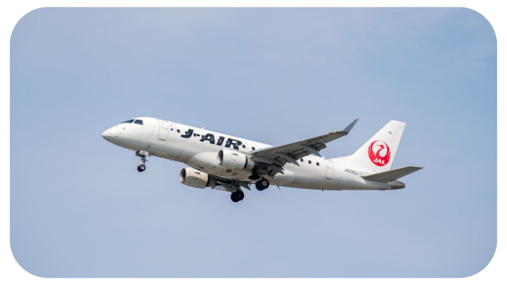A J-Air aircraft, part of Japan Airlines (JAL), is captured mid-flight with landing gear extended, set against a clear blue sky.