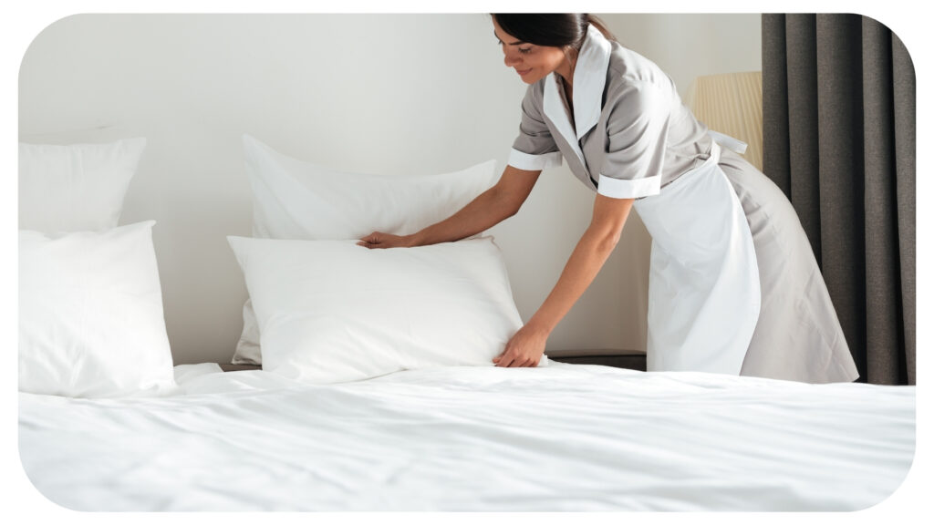 Young Hotel Maid Setting up Pillow on Bed