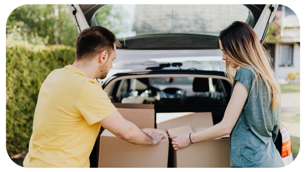 Calm couple putting carton boxes into car trunk