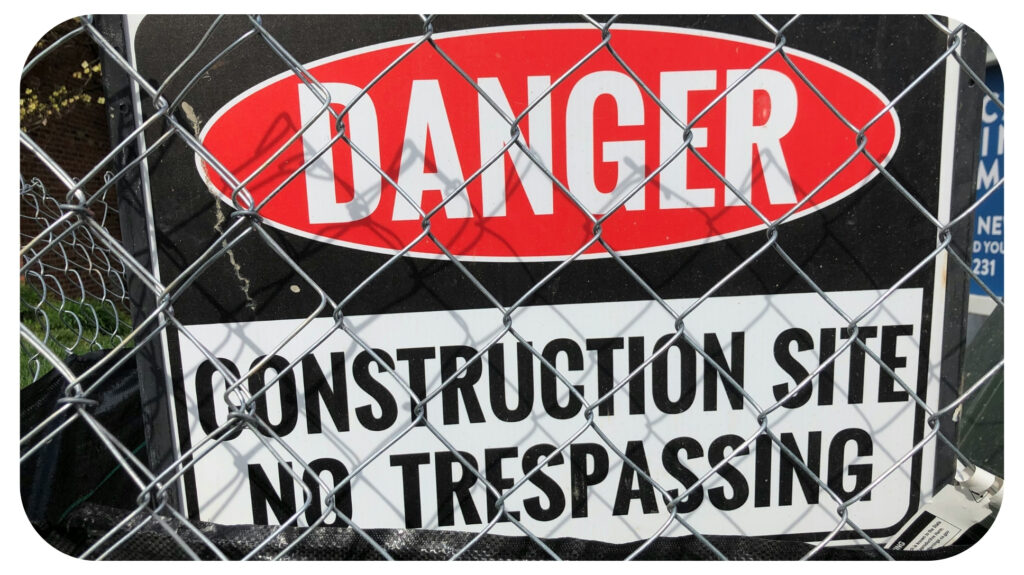a sign on a fence that says danger construction site no trespassing