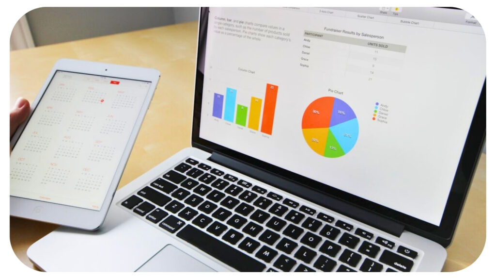 A laptop displaying colourful bar and pie charts next to a tablet showing a full-year calendar, representing data analysis, planning, and digital productivity.