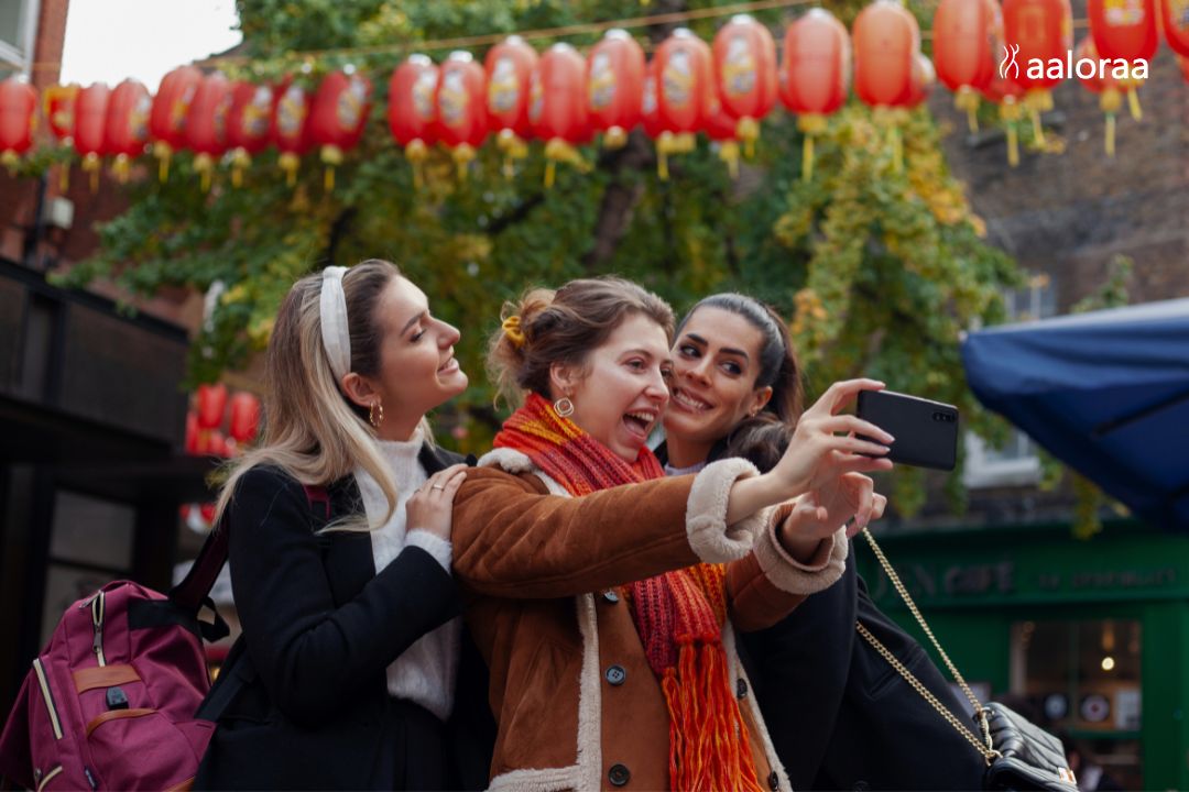 Three stylish women taking a selfie outdoors in a vibrant city setting, showcasing friendship, street fashion trends and capsule wardrobe inspiration featured on MostInside lifestyle blog.