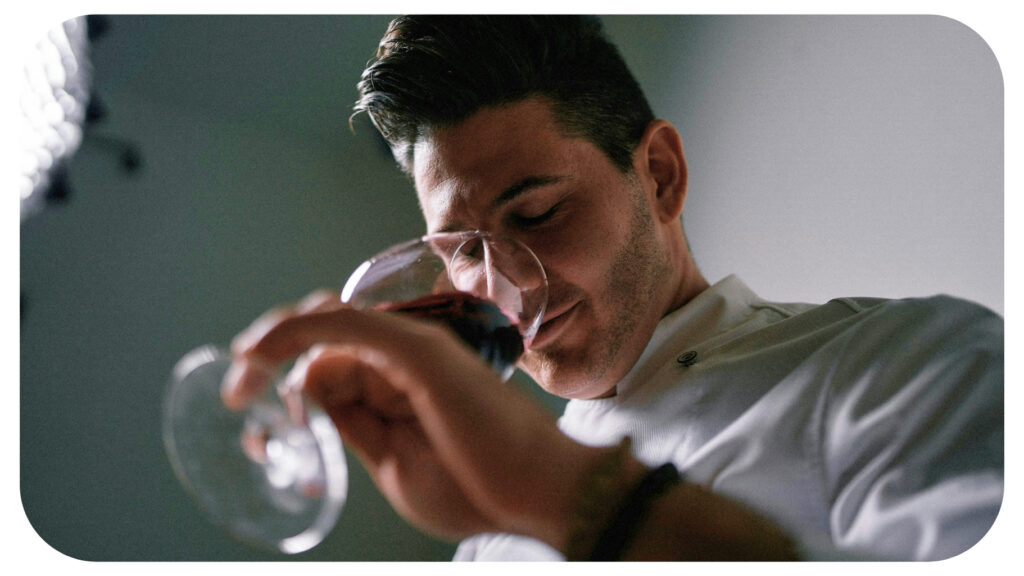 Professional food and wine taster smelling red wine to identify flavour notes and aroma profiles while training the palate for better tasting recognition and sensory analysis.