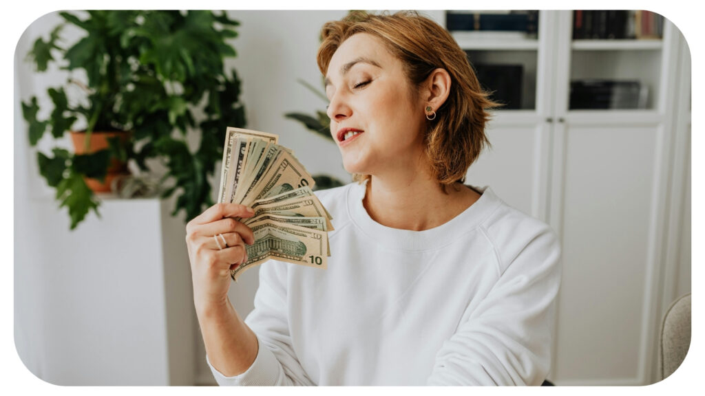 Woman holding cash at home symbolising financial independence recovery confidence and rebuilding personal security after financial abuse and separation.