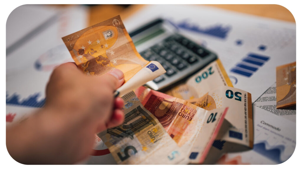 Person holding euro banknotes near a calculator and financial documents, illustrating legal fees, government fines, regulatory penalties, compliance costs, and the financial consequences of failing to follow legal requirements.