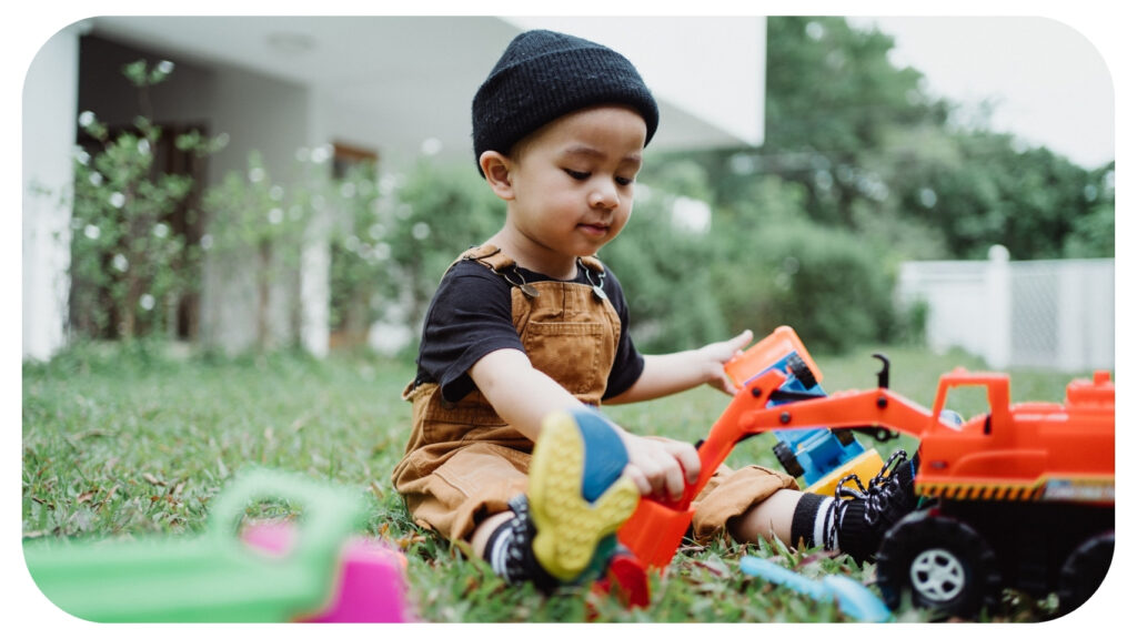 Young child playing with construction toys in a safe suburban backyard, illustrating a kid-friendly backyard design that encourages active outdoor play, imaginative learning, physical development, child-safe landscaping, and family-friendly outdoor living.